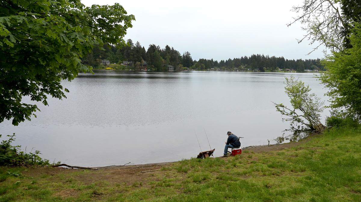 A fisherman enjoys a pleasant afternoon along the shoreline at Wanschers Park in Lacey.. The park is close to two controversial apartment complex projects that many nearby residents opposed.