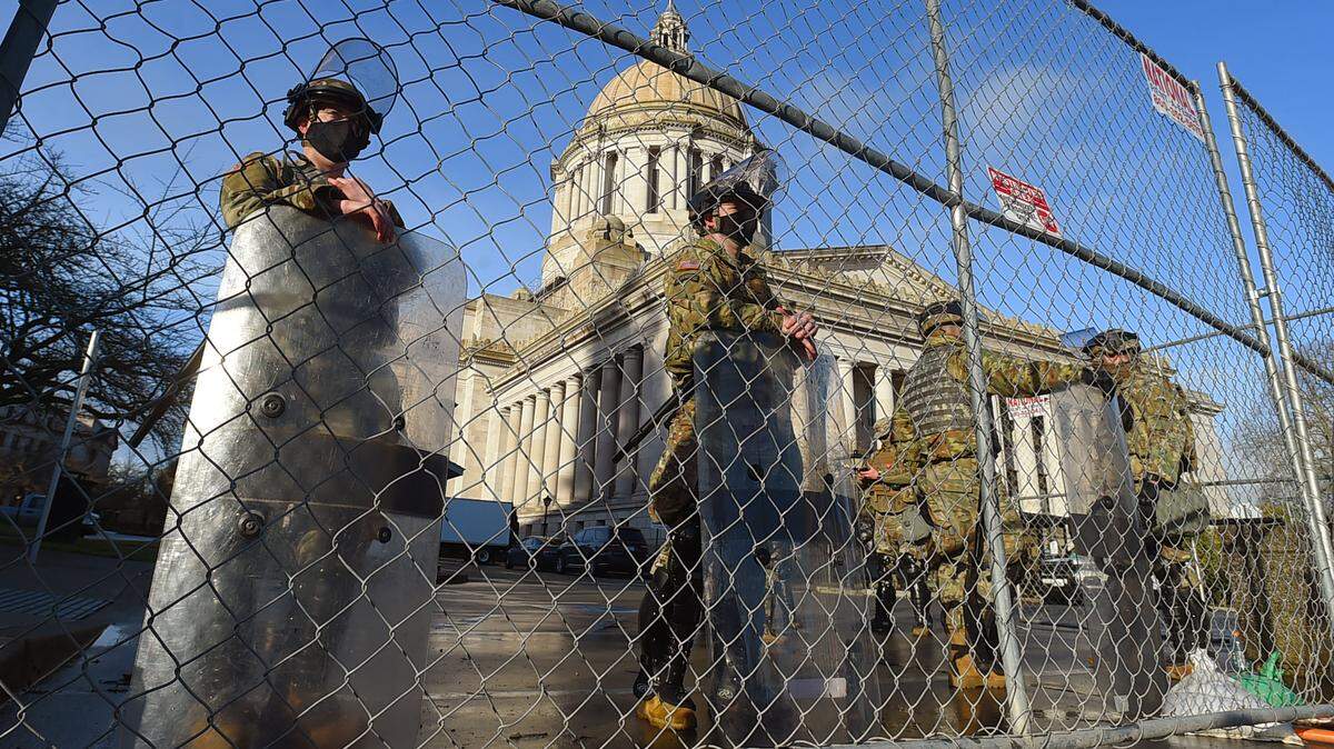 Two years ago, A large contingent of Washington State Patrol and National Guard personnel wearing riot gear stand watch along the massive perimeter fencing that surrounds buildings at the state Capitol in Olympia.