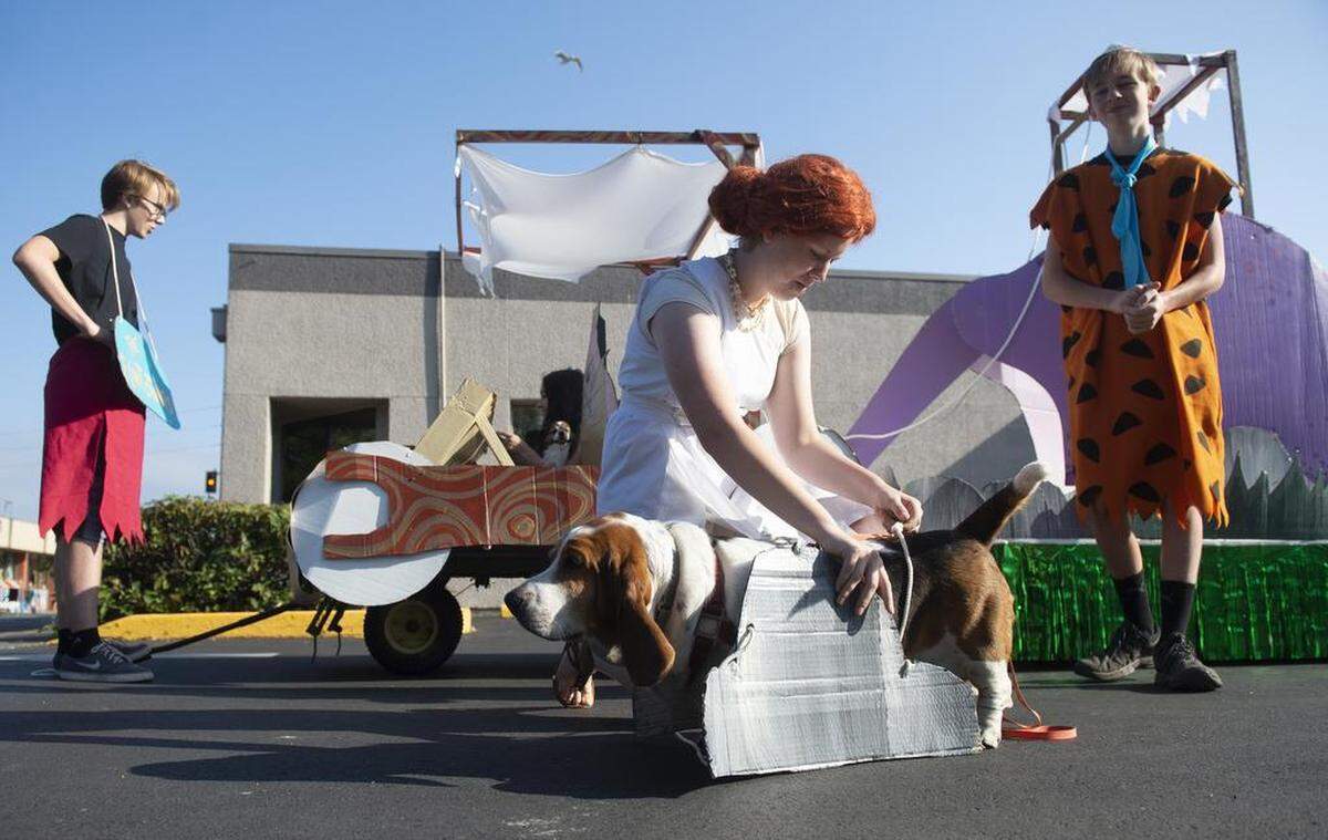 Roslyn Tobeck, 15, of Olympia prepares Jasmine the Basset hound as she waits with Morrison Ball (from left), 15, Olivia Marty (seated), 14, and Mason Ball, 13, as they wait with their Flintstones-inspired floats before the start of the 89th annual Pet Parade in downtown Olympia on Saturday.