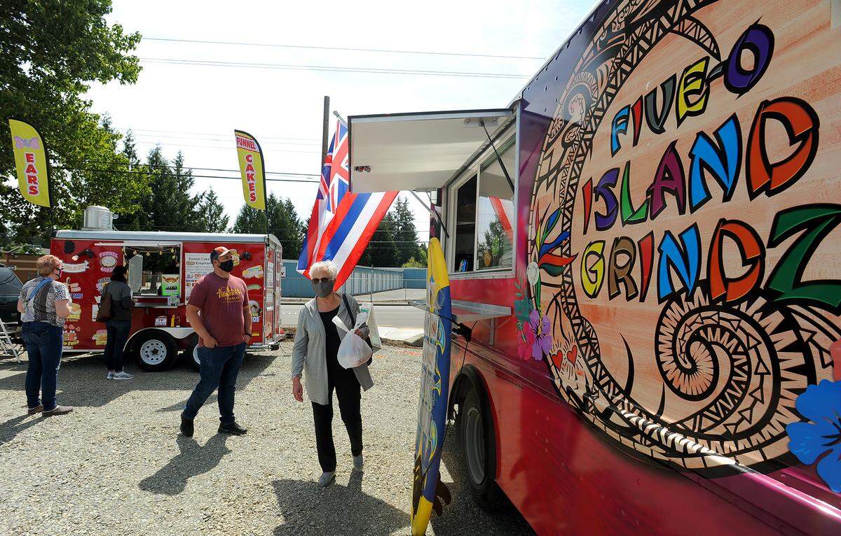Ruth Weigelt picks up her lunch from the Five-O Island Grindz food truck April 29, 2021 at the City of Lacey’s new Food Truck Depot. Also serving on site was the Funnel of Love food truck, which offered treats ranging from funnel cakes to elephant ears.