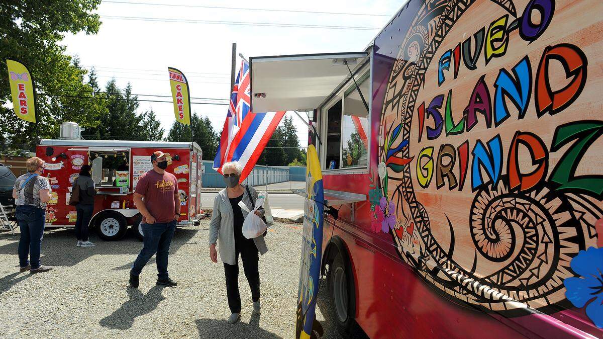 Ruth Weigelt picks up her lunch from the Five-O Island Grindz food truck April 29, 2021 at the City of Lacey’s new Food Truck Depot. Also serving on site was the Funnel of Love food truck, which offered treats ranging from funnel cakes to elephant ears.
