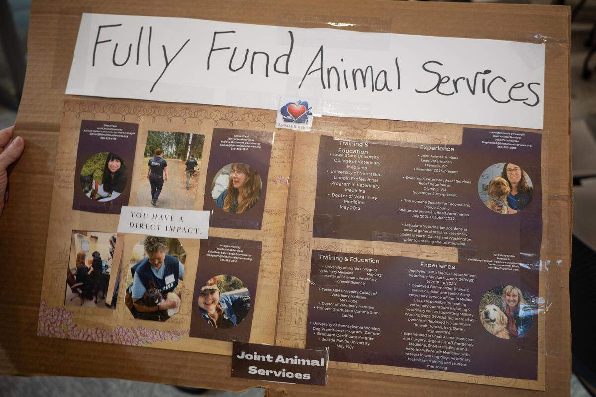 Debra Curl, a Joint Animal Services volunteer, held this sign at a Board of County Commissioners meeting on Friday, Sept. 26, 2025. Curl said she showed up to protest a a proposed funding cut for JAS.