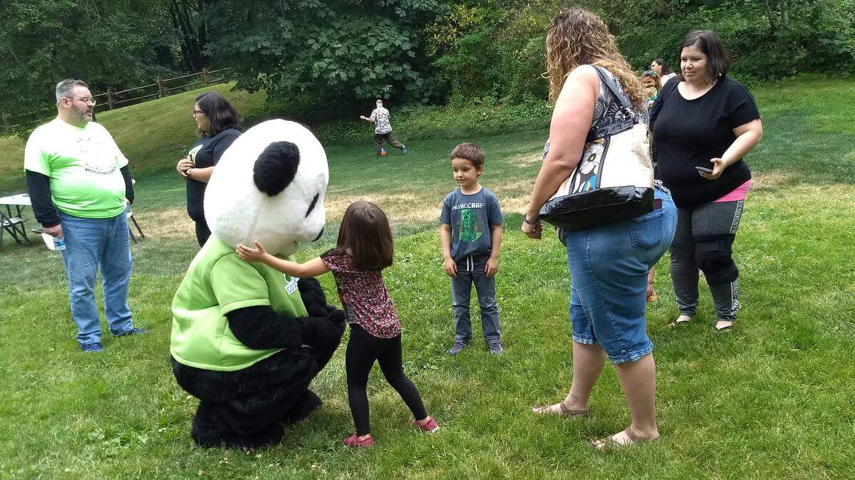 Four-year-old Hailey Browning, center, hugs a panda character at Thursday’s picnic while Chase Browning, 5, Trista Mason and mom Shaylynn Lenoir, right, look on. The event at Tumwater Historical Park celebrated families that were reunited after the children were taken away by the courts.