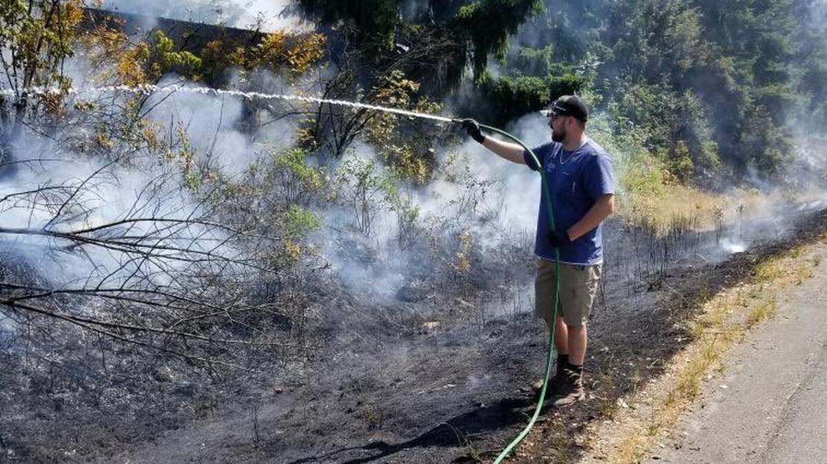 All County Rooter & Repair workers help put out a fire on the side of northbound I-5 in Thurston County on Wednesday afternoon.