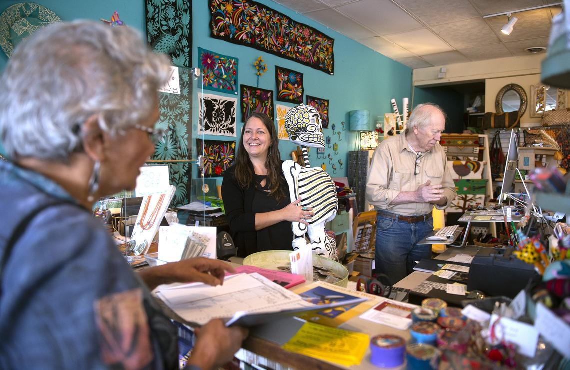 New co-owner Stacy Muguet (center) talks with customer Kali Basi of Yelm as former owner Dick Meyer helps with the transition at Traditions Fair Trade & Cafe in downtown Olympia.
