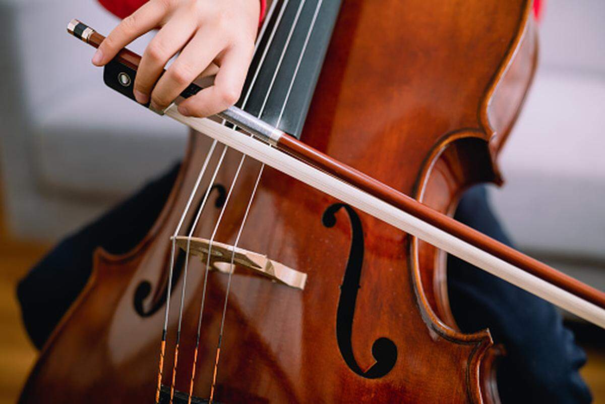 Young boy practicing cello indoors
