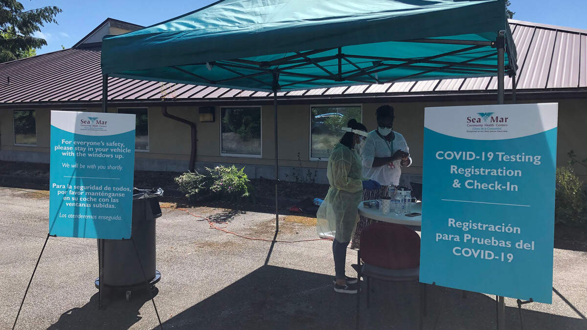 Two nurses prepare and package nasal swabs used to test patients for COVID-19, outside of West Olympia’s Sea Mar Community Health Center.