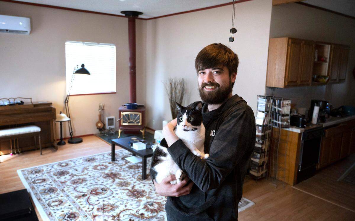 Ashton Burcher with his cat, Butters, at the rental home he shares with his huband in Tenino, Washington, on Friday, May 20, 2022. A past bankruptcy kept Burcher from getting accepted for other rentals, forcing the couple to live in hotels for nine monts before finding a private landlord willing to take a chance. “It’s worked out great,” Burcher said.