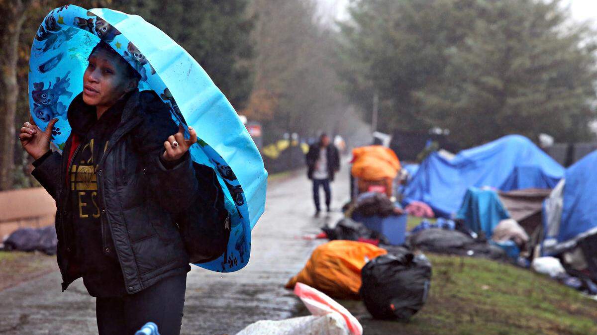 An encampment resident takes cover from the rain under a wading pool.