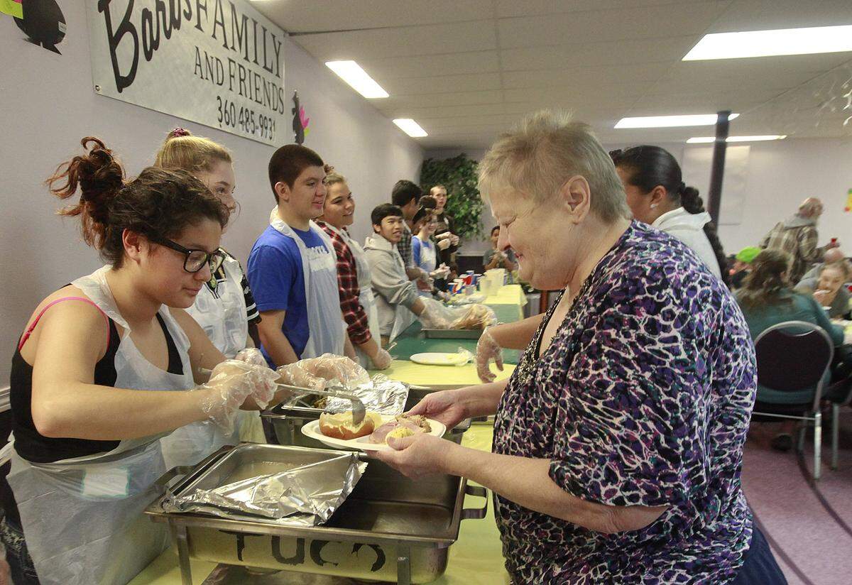 Volunteer Haliya Charley fills Terry Thomas’ plate during Barb’s Family and Friends Thanksgiving meal Wednesday at The United Churches, downtown Olympia. Now in it’s 45th year the annual meal was started by Barb O’Neill and is kept going by her son Rodney after her passing in 2008.