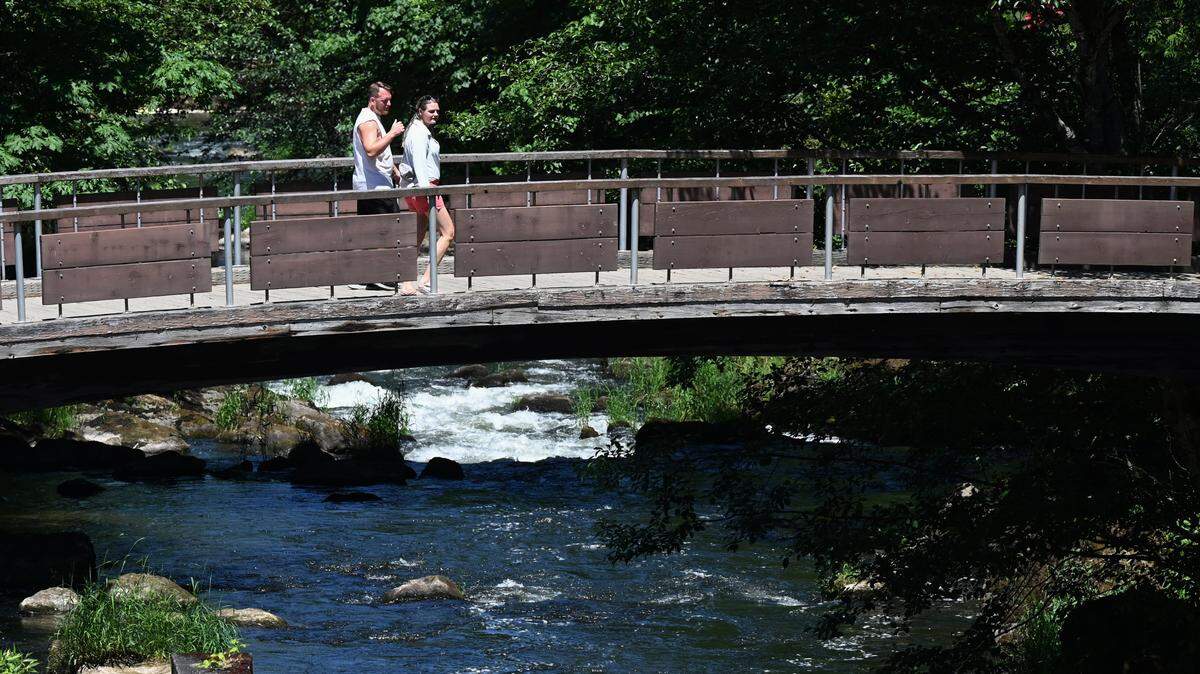 Visitors to Brewery Park at Tumwater Falls enjoy a warm walk across the cold Deschutes River on Monday as a forecasted short spell of hot weather makes an appearance early in the week.