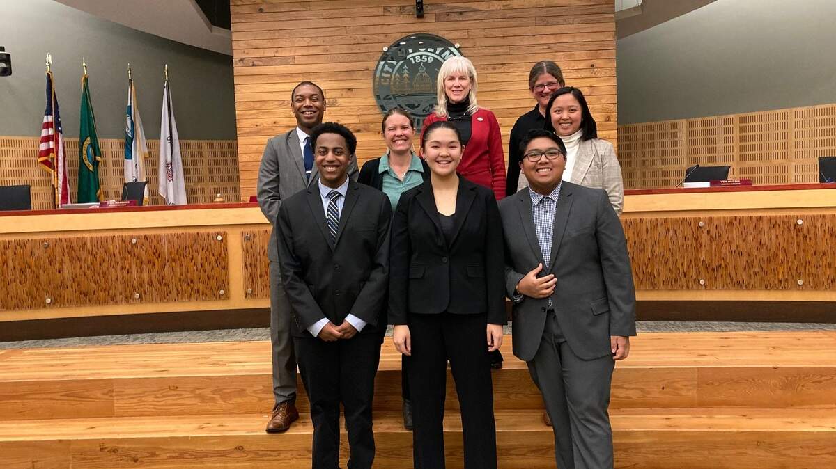 Youth representatives Tre Simons, Christine Zhang and Gavin Cruz stand with members of the Olympia City Council on Oct. 30 following the unanimous approval to stand up a youth council. 
