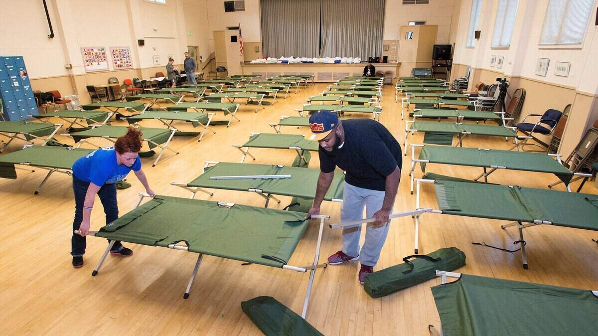 Omar Rashid, right, an outreach worker with Community Youth Services, and volunteer Linda Rick, help set up about 40 cots for a cold-weather shelter at Beacon Senior Center in Tacoma on Dec. 14, 2015. The city has announced it will be adding similar resources this winter.