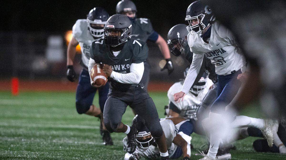 River Ridge running back Darion Brown breaks away from Olympia defender Logan Matthews for a 70-yard touchdown run to open scoring in Friday night’s high school football game at South Sound Stadium in Lacey on Friday, March 19, 2021.