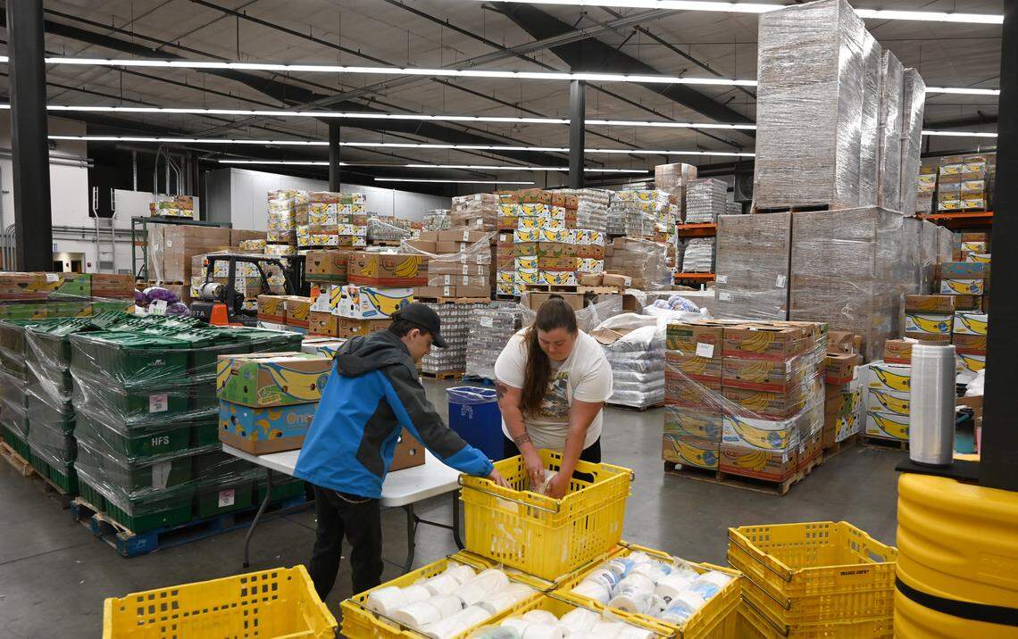 Volunteers Jullysa Daylynn and Matty Graffagnino pack paper products in the Thurston County Food Bank’s 30,000-square-foot warehouse in Olympia, Wa. on Friday, May 9, 2025.