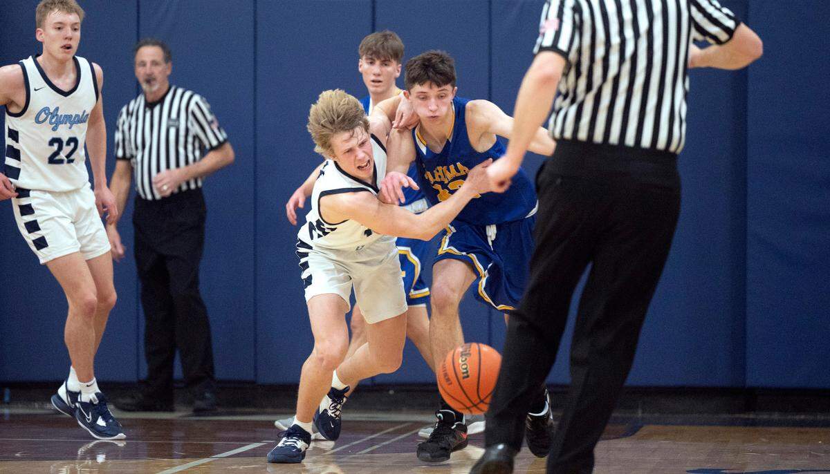 Olympia’s Drew Carlson (left) battles Tahoma’s Dalton Brown as they chase after a loose ball during Saturday night’s boys basketball game at Olympia High School in Olympia, Washington, on Feb. 11, 2023. Olympia won the game, 70-50.