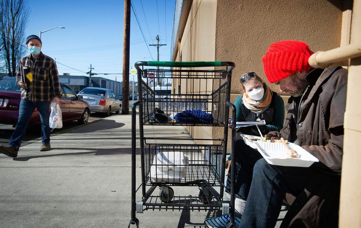 Volunteer Eliza Ramsey of Seattle talks withg Dana Smith during the Point in Time homeless census outside the Salvation Army shelter in downtown Olympia on Friday.
