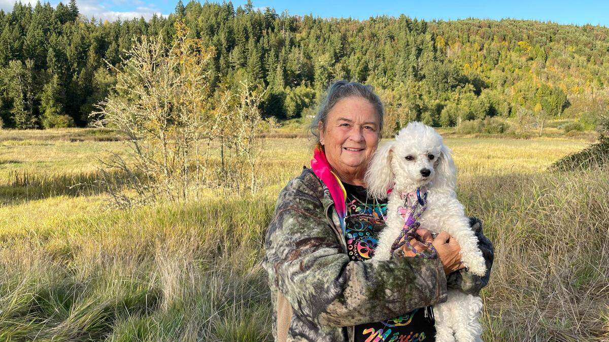 Marcia Berger and her dog, Selene, stand on the land her family has sold to the Nisqually Land Trust. The land is a floodplain for Ohop Creek, a tributary of the Nisqually River.