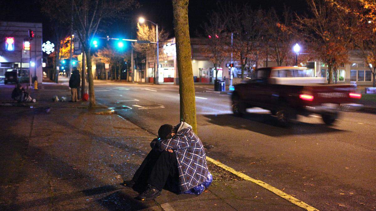 A young man huddles in the cold along State Avenue in downtown Olympia in 2012.