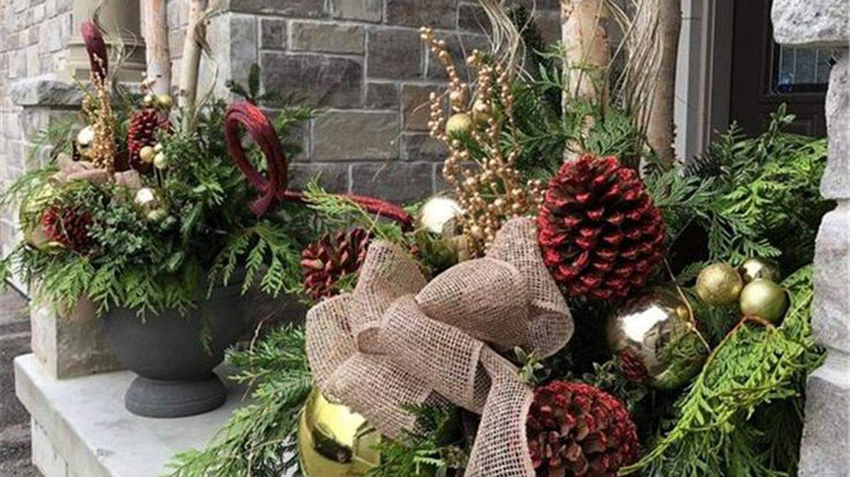 To decorate your porch for the holidays, harvest branch tips of hardy evergreens and poke the cut stems into the soil of your patio and porch pots. Mix the greens or just use one type of foliage and adorn with weatherproof ornaments or bows. 