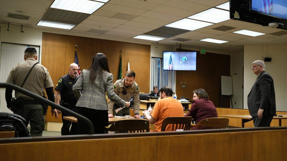 Josiah Sweeney, 31, (center) cleans his fingers after being fingerprinted by Thurston County Sheriff deputies at the conclusion of his sentencing hearing on Monday, Feb. 27. He sat next to his defense attorney Angela Colaiuta as Prosecuting Attorney Jon Tunheim (right) looked on.