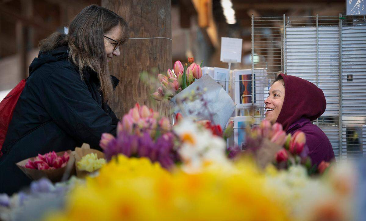 Debi McNutt of Olympia buys fresh-cut flowers from Maria Magana of Ojeda Farms on the first day of summer season at the Olympia Farmers Market in Olympia, Washington, on Friday, April 1, 2022.