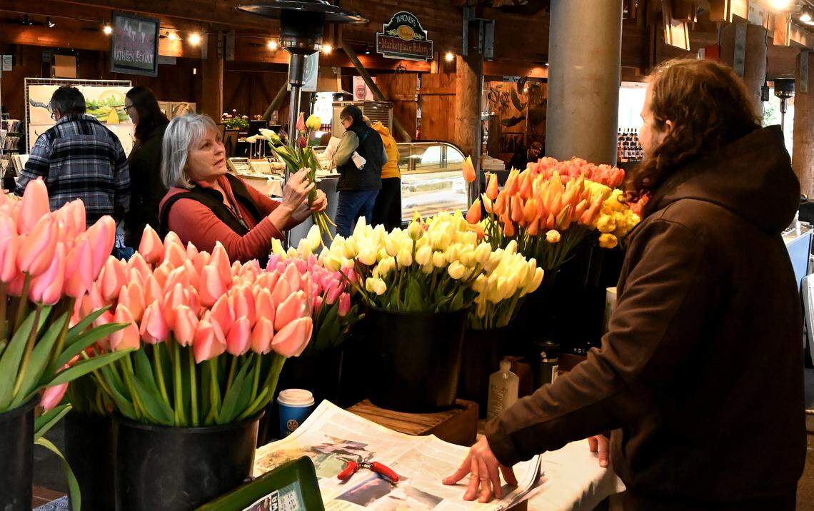Signe Feeney picks a bouquet with help from Constellation Farm co-owner Jonathan Berger on Thursday, April 4, opening day of high season at Olympia Farmers Market.