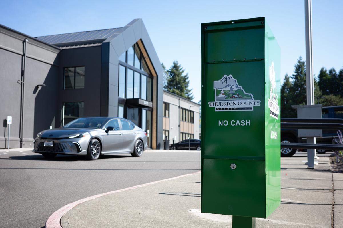 A driver approaches a green payment drop off box outside The Atrium, Thurston County’s administrative headquarters. Property tax payments may be submitted by mail, in-person at Treasurer’s Office in The Atrium or at this drop off box. 