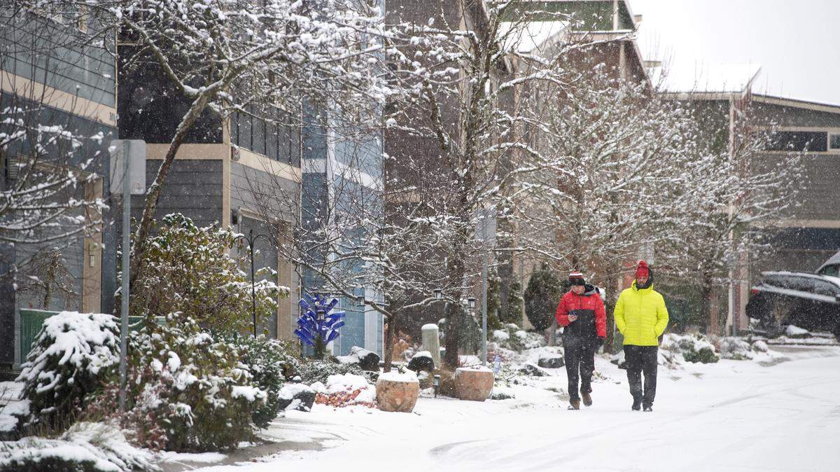 Walkers on the snow-covered streets on Tumwater Hill in Tumwater, Washington, on Friday, Dec. 2, 2022.