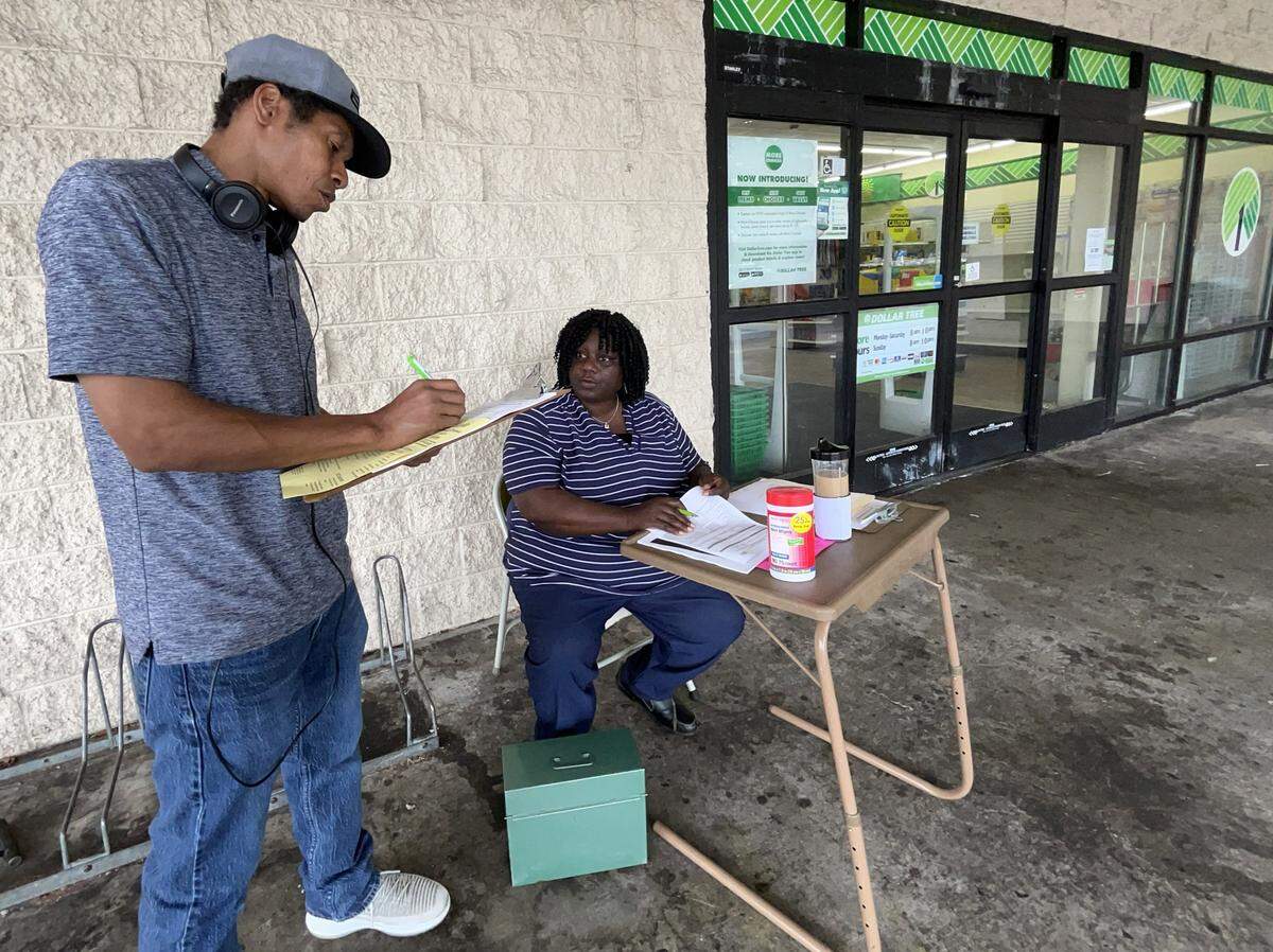Arnita Jones with Adonai Counseling and Employment Services answers a few questions from Tommy Kirk as he fills out a questionnaire after stopping by organization’s outreach table set up in Lacey on Aug. 15. 