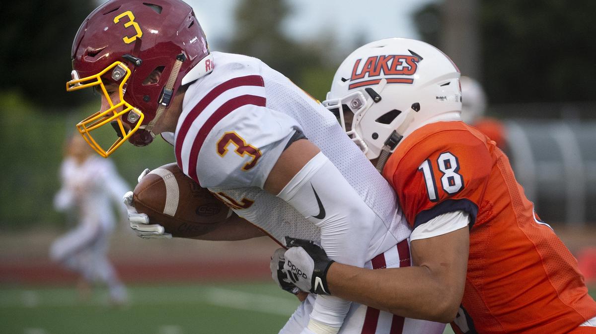 Capital wide receiver Chris Penner drags Lakes defensive back Philip Riley into the end zone for a touchdown reception to open scoring in Friday night’s season-opening football game at Harry E. Lang Stadium in Lakewood on Aug. 31, 2018.