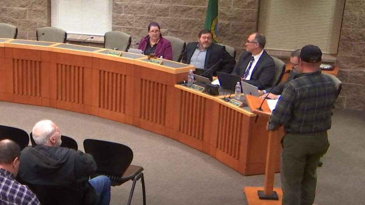 Aldea Glen resident Shane Hunter addresses Lacey City Council at the podium Thursday night. Two council members appeared in person, while three appeared remotely.