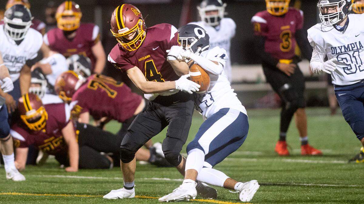 Olympia defensive back Alfredo Ramirez-Cortes (right) rips the ball away from Capital wide receiver Deonte Burns for a turnover during Friday night’s Spaghetti Bowl crosstown-rivalry football game at Ingersoll Stadium in Olympia, Washington, on March 12, 2021.