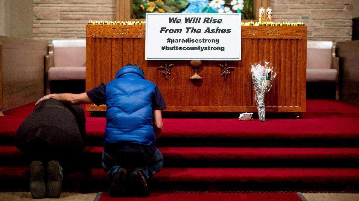 Mourners pray during a vigil for Camp Fire victims on Nov. 18 in Chico, California. The blaze killed dozens and destroyed more than 10,000 structures.