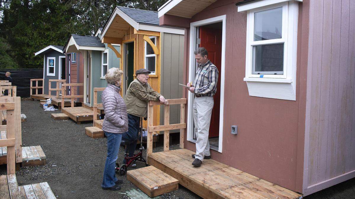 Maureen Wells (left) and Bruce Wells of the Unitarian Universalist Church in Olympia talk with Charles Schneider of Tumwater in 2019 about how to expand homeless outreach like the Plum Street Village in downtown Olympia to other communities. The village features 40 tiny homes, a hygiene trailer and kitchen area in a city-owned lot south of the former Olympia City Hall complex.