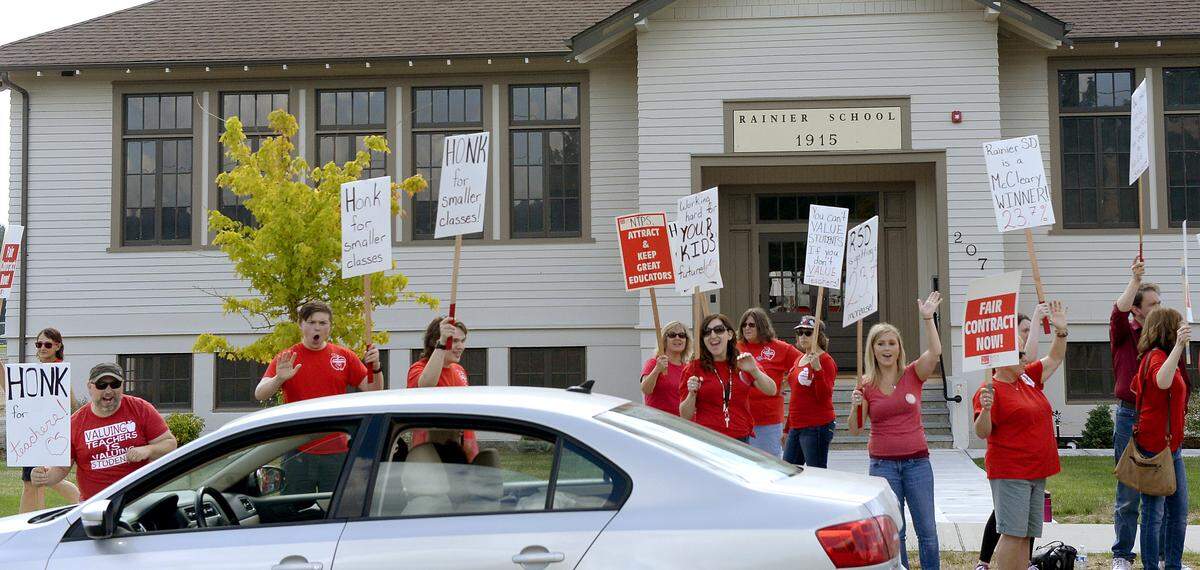Teachers and their supporters waive signs along Centre Street in Rainier on Monday. The district now says it has a tentative contract agreement with the Rainier Education Association and that school will start Thursday.