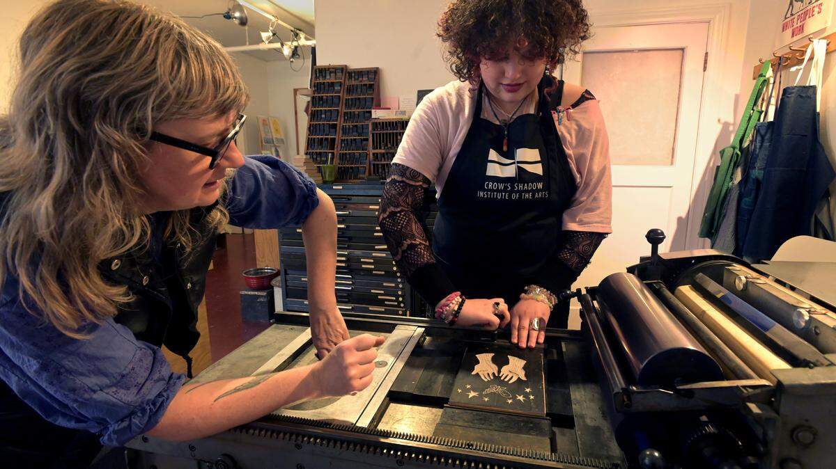 Artist J. Hukee assists Avanti High School junior Nico Kalama-Arch with setting her newly created printing block onto the printing press at the Olympia Knitting Mills last March. The class is part of the Avanti High School ACE (Apprenticeships for the Creative Economy) pilot program where artists work with students in an internship setting. Olympia’s Avanti is rated as one of the state’s top 10 alternative high schools.