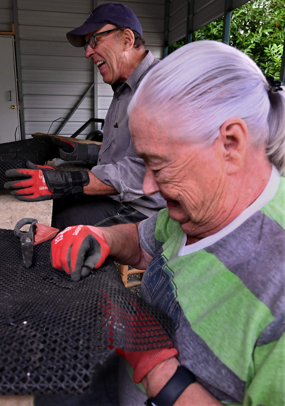 Olympia Oyster Seeding Project coordinator Dan Mazur along with volunteer Joan Wubbena work preparing planting bags at his home near Squaxin Park on July 14, 2025. Using team of volunteers the daily plantings will run at selected, tidal-dependent times through the weekend of July 20, and includes performing oyster seed counts, filling oyster grow bags and finally planting them on selected south sound beaches. Further information on the project can be found online at olympiaoysterseedplantingproject.org or by calling 360-292-0736.