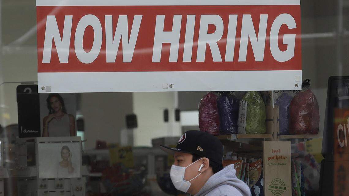 A man wears a mask while walking under a Now Hiring sign at a CVS Pharmacy. Things will look different as we emerge from staying at home.