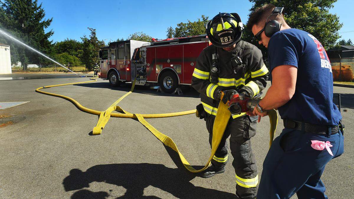 Lt. Evan Parnell (right) assists firefighter Christian Valdez while firefighter Ryan Fakkema monitors the water spray during a training drill at the South Bay Fire Department’s training center on Aug. 2, 2023.