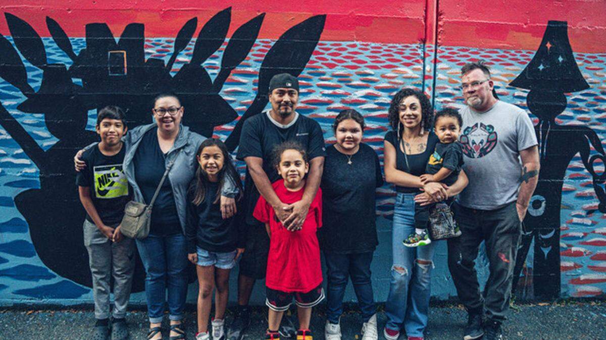 From left, artists Brianne McCloud, Kyle Sanchez and Erica Sanchez, and Nisqually Arts Coordinator Chris Gerber stand with their children in front of the new mural in downtown Olympia created in honor of the Nisqually tribe.