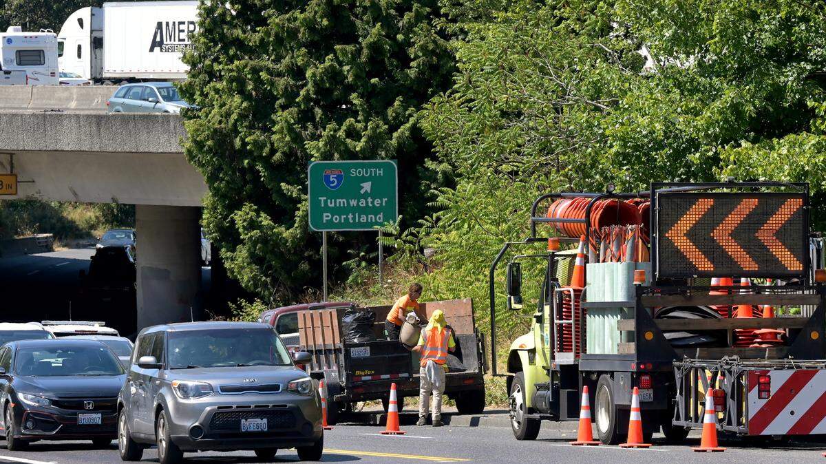 Clean-up crews remove garbage bags filed with material from a homeless encampment along Pacific Avenue in Olympia on August 8, 2022.