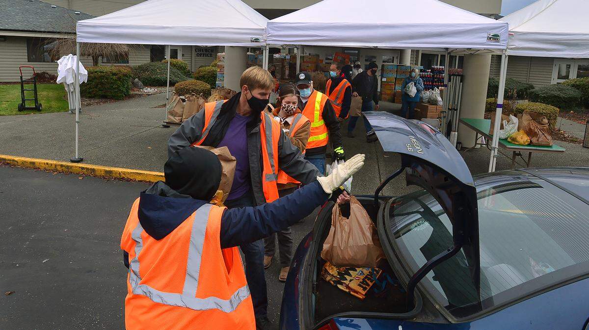 Thurston County Food Bank development director Judy Jones opens the trunk of an awaiting car as volunteers and staff give away holiday meals Nov. 18 at Mountain View Church in Tumwater.