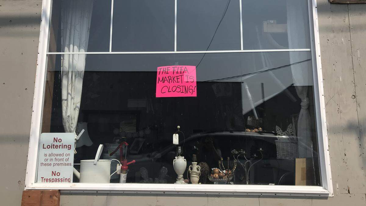 A paper sign taped to the window of the Olympia Flea Market announces its closure.