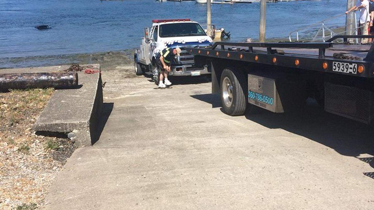 See the black dot in the water behind the tow truck? That’s an SUV.