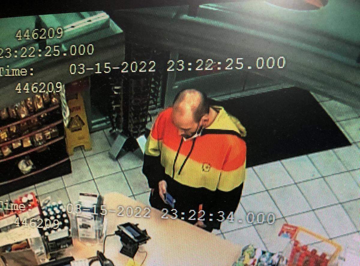 A balding man in a hooded sweatshirt colored orange, yellow and black stands in gas station shop at 670 Trosper Road Southwest at 11:22 p.m. on Tuesday, March 15. Tumwater police allege he stole a truck occupied by a sleeping 10-month old boy.