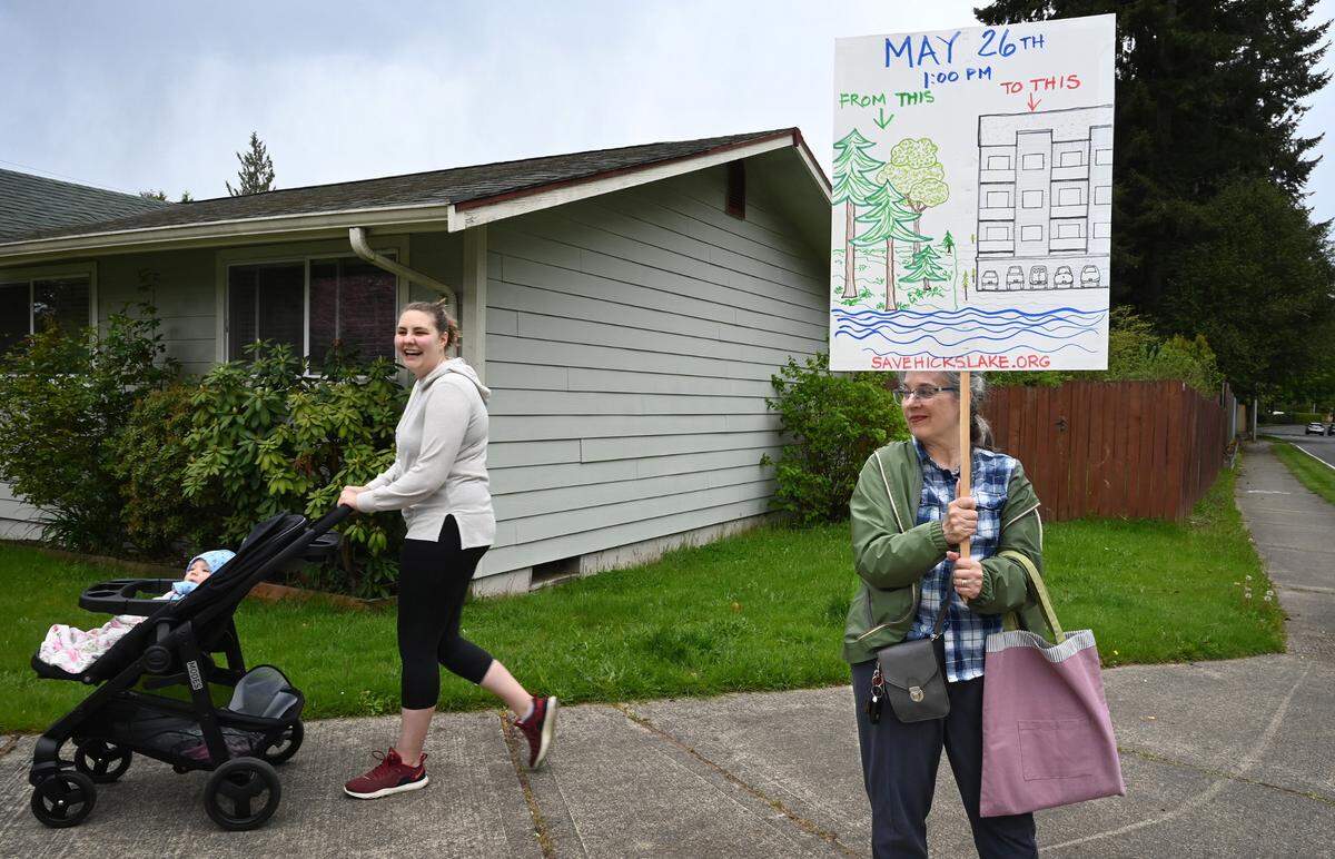 Erin Puente walks with her daughter Savannah as they pass by Janet Ikeda as she joins fellow neighbors to protest the proposed apartment complex in their Hicks Lake neighborhood along Ruddell Road in Lacey, Washington, on Friday, May 13, 2022.