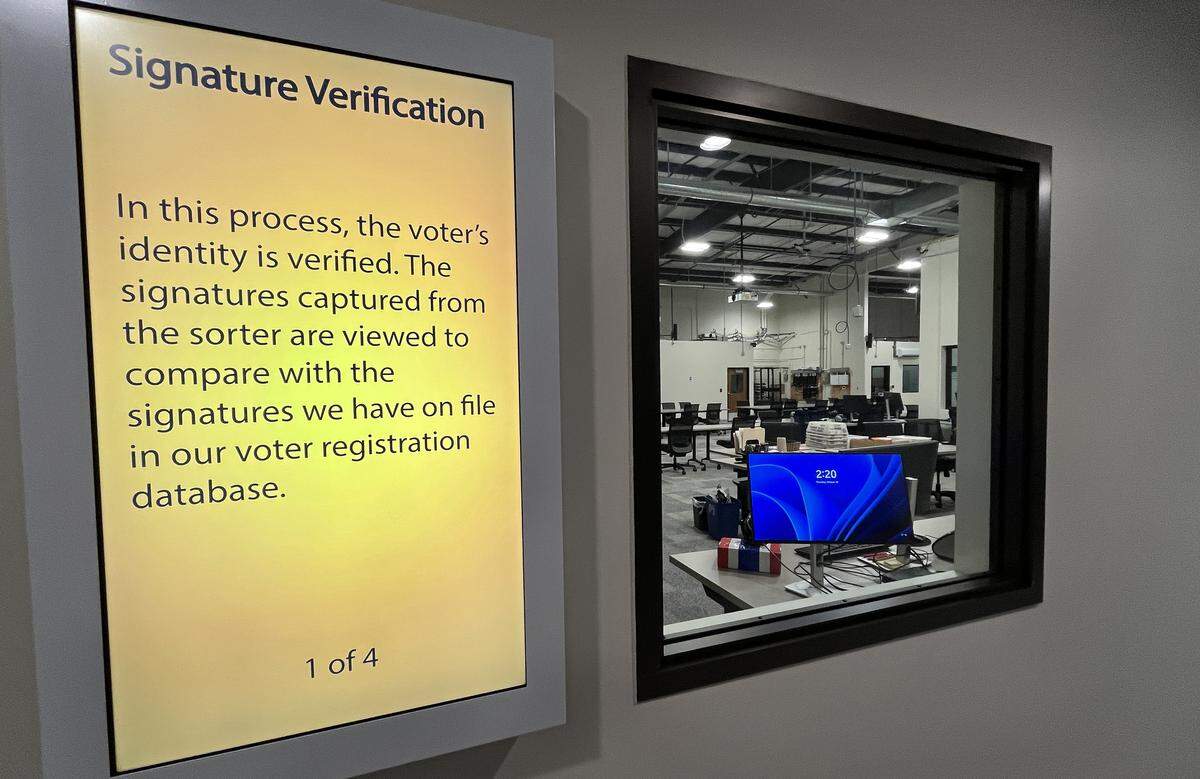 Visitors can walk through an observer corridor with reinforced windows into the facility. Vertical screens are spaced out along this corridor, each of which cycle through text describing the ballot processing step in view.