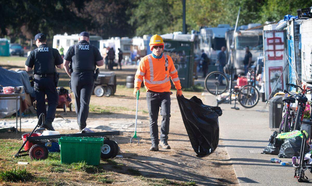 City work crews, police and crisis outreach workers gather to help with the clearing and relocation of residents living in their vehicles at the permitted RV parking area along Ensign Road in Olympia, Washington, on Wednesday, Sept. 21, 2022. The city plans to have the street completely cleared by mid-October.