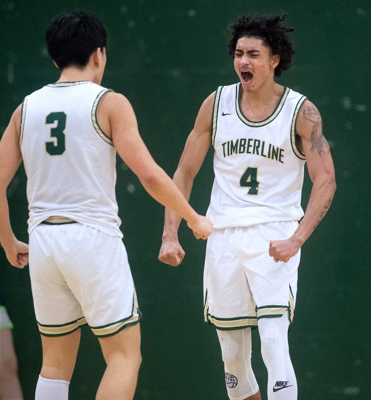 Timberline’s Brooklyn Hicks celebrates with teammate Tyler No during Saturday night’s West Central III/Southwest bidistrict tournament boys basketball opening-round game against the Todd Beamer Titans at Timberline High School in Lacey, Washington, on Feb. 12, 2022. Timberline won the game, 70-40.
